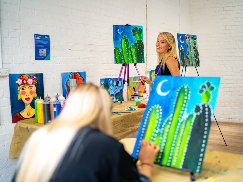 A teacher demonstrates how to paint cactus at an acrylic painting class in Bristol